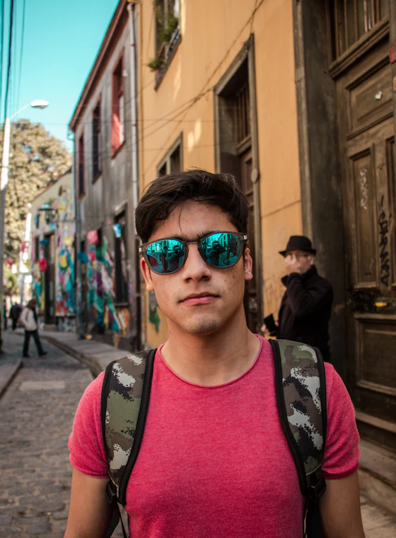 A young traveller with a backpack and sunglasses on a city street